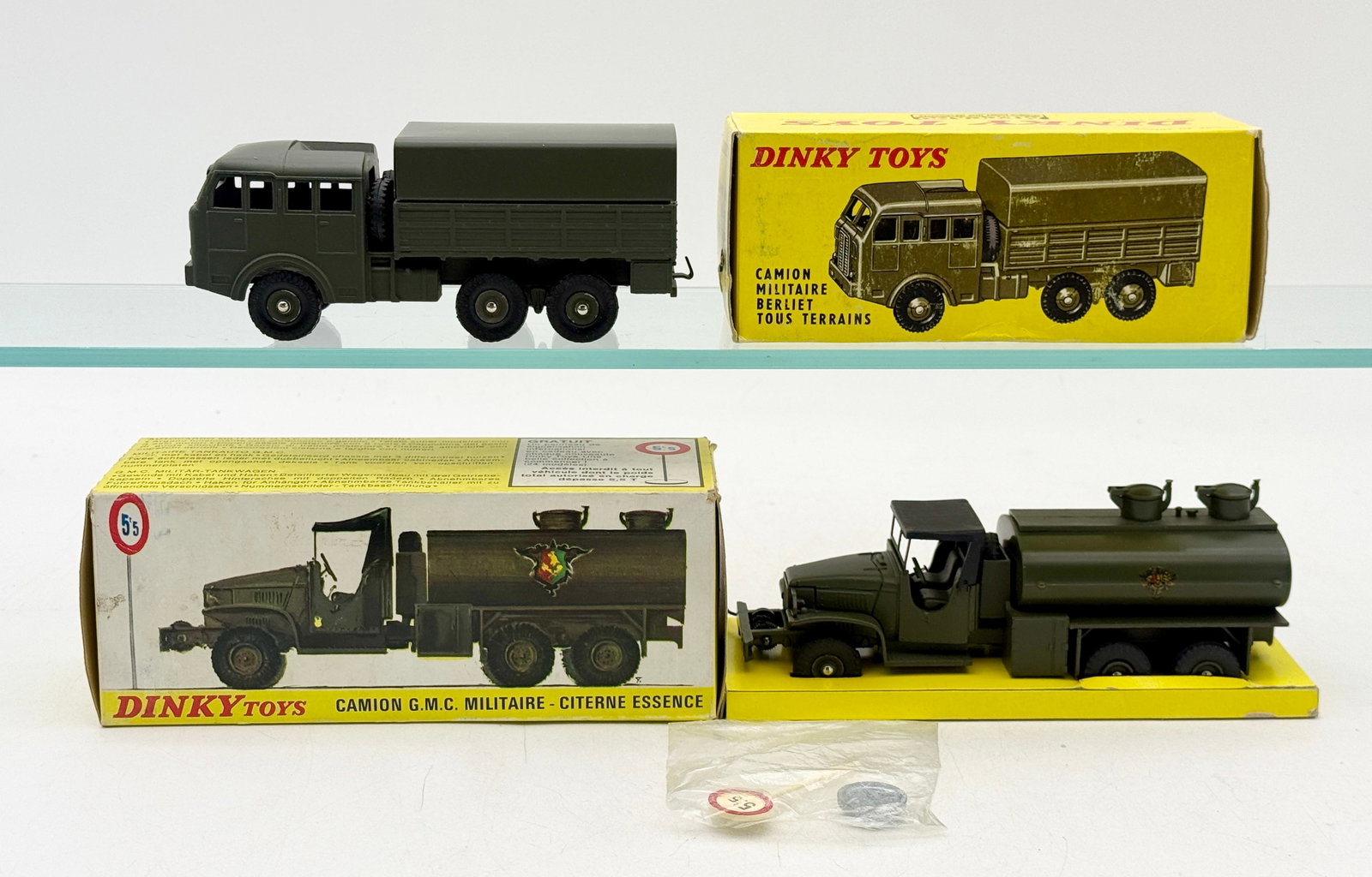 Two French Dinky Toys Die-Cast Military Vehicles with Original Boxes: This set of vintage French Dinky Toys includes a Berliet all-terrain truck and a GMC military fuel tanker. Both die-cast vehicles are finished in olive-drab and come with their original illustrated ca