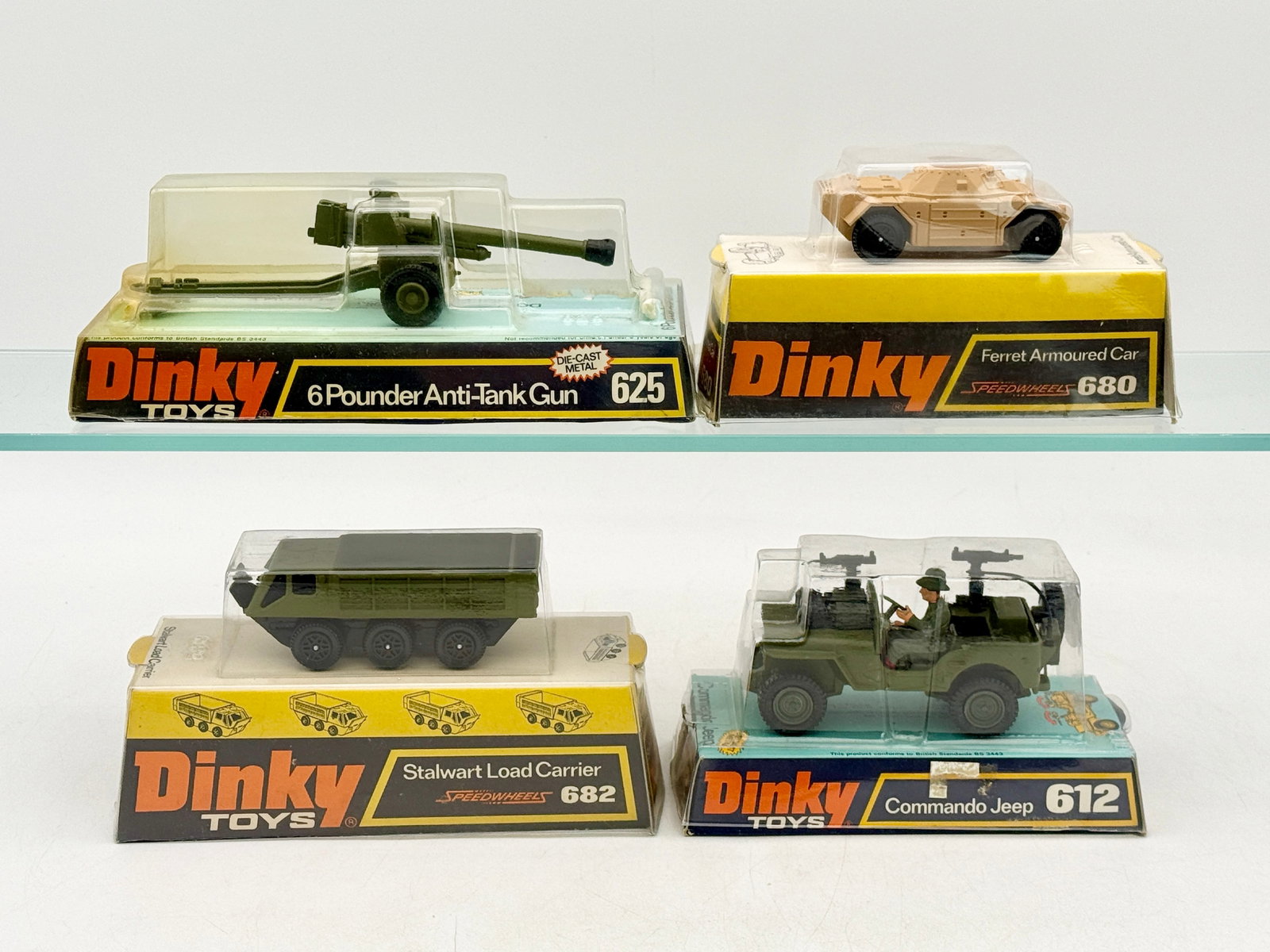 A Group of Vintage Dinky Toys Military Vehicles: A group of vintage Dinky Toys military vehicles in original bubble-pack packaging. These models feature die-cast metal bodies with olive green and tan paint finishes and plastic detailing. The collect