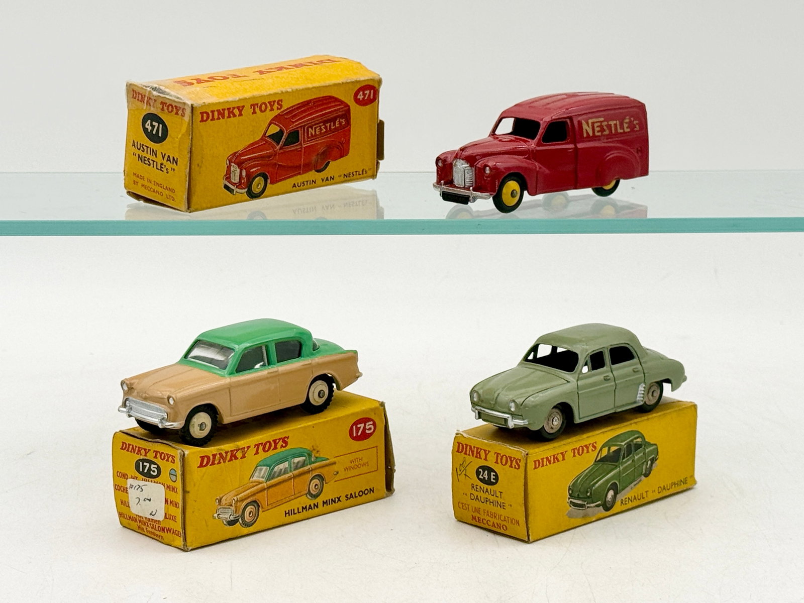 A Trio of Dinky Toys Die-Cast Model Vehicles with Boxes: Three Dinky Toys die-cast metal vehicles by Meccano Ltd. comprising an Austin Nestleâ€™s van, a Hillman Minx Saloon, and a Renault Dauphine. Each vehicle is accompanied by its original yellow 