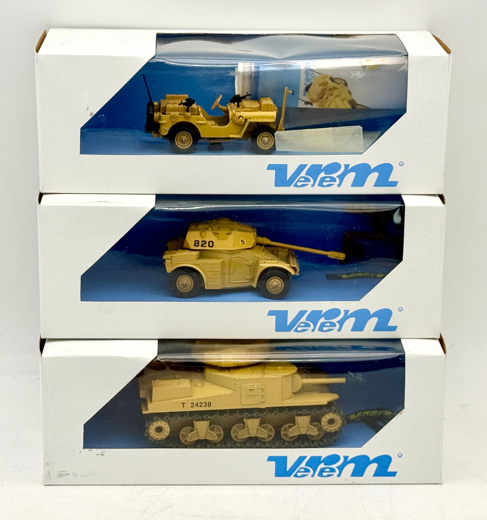 A Trio of Verem Die-Cast Desert Tan Military Vehicles: This trio of die-cast military vehicle models by Verem includes a General Grant M3 tank, a Panhard AML 90 armored car, and a Special Air Service Jeep Commando. Each model is finished in a uniform dese