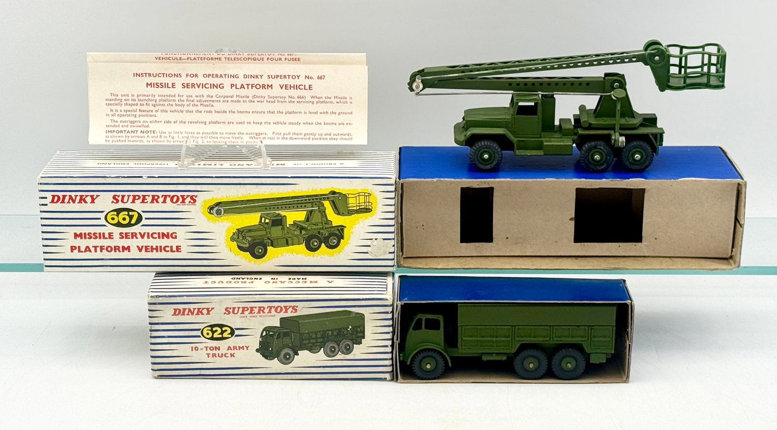 A Pair of Dinky Supertoys Military Vehicles with Original Boxes: This pair of Dinky Supertoys includes the No. 667 Missile Servicing Platform Vehicle and the No. 622 10-Ton Army Truck. Each vehicle is constructed of die-cast metal with an olive drab green finish an