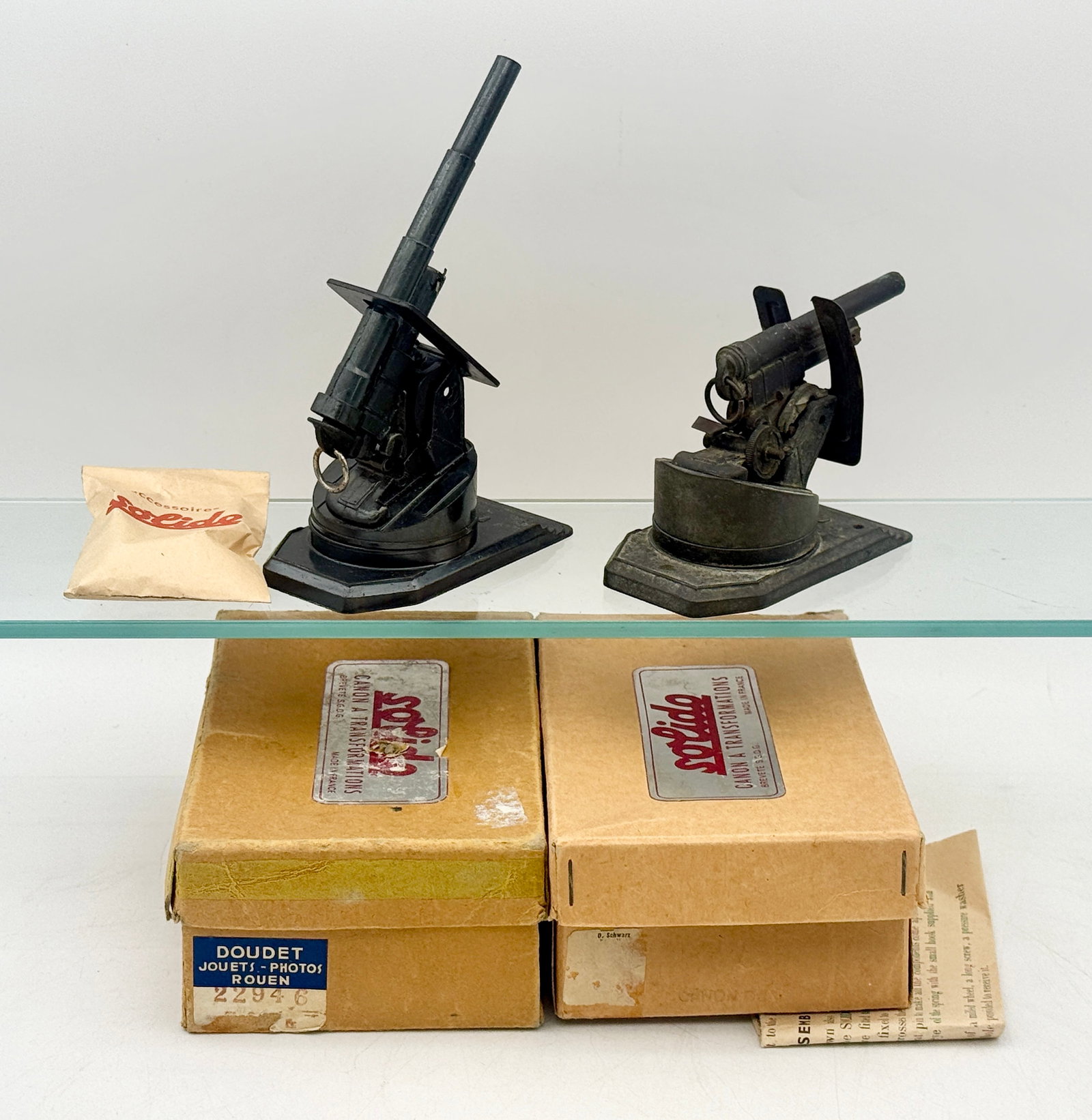 Two Vintage Solido Canon a Transformations Die-Cast Toy Artillery Pieces: This pair of Solido Canon a Transformations toy artillery pieces is constructed from dark-finished die-cast metal and includes original cardboard packaging. Each model features an adjustable barrel an