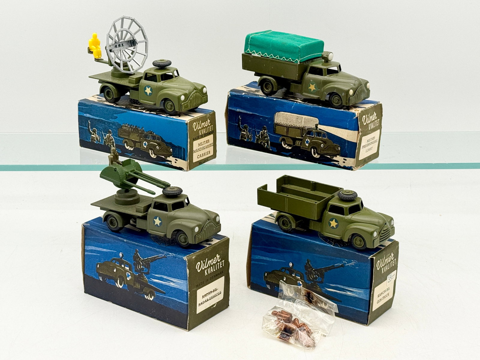 A Collection of Vilmer Die-Cast Military Transport Vehicles with Boxes: A collection of Vilmer die-cast metal military transport vehicles manufactured in Denmark. The lot includes various configurations in olive drab with yellow star decals, featuring a radar unit, an ant