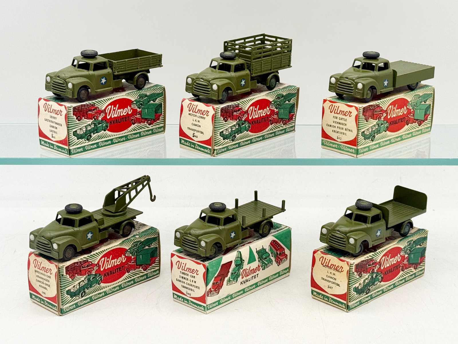A Collection of Vilmer Military Die-Cast Model Trucks: A collection of Vilmer die-cast military trucks with original illustrated packaging. Each Danish-made vehicle is finished in olive drab paint with white star decals, black rubber tires, and various bo