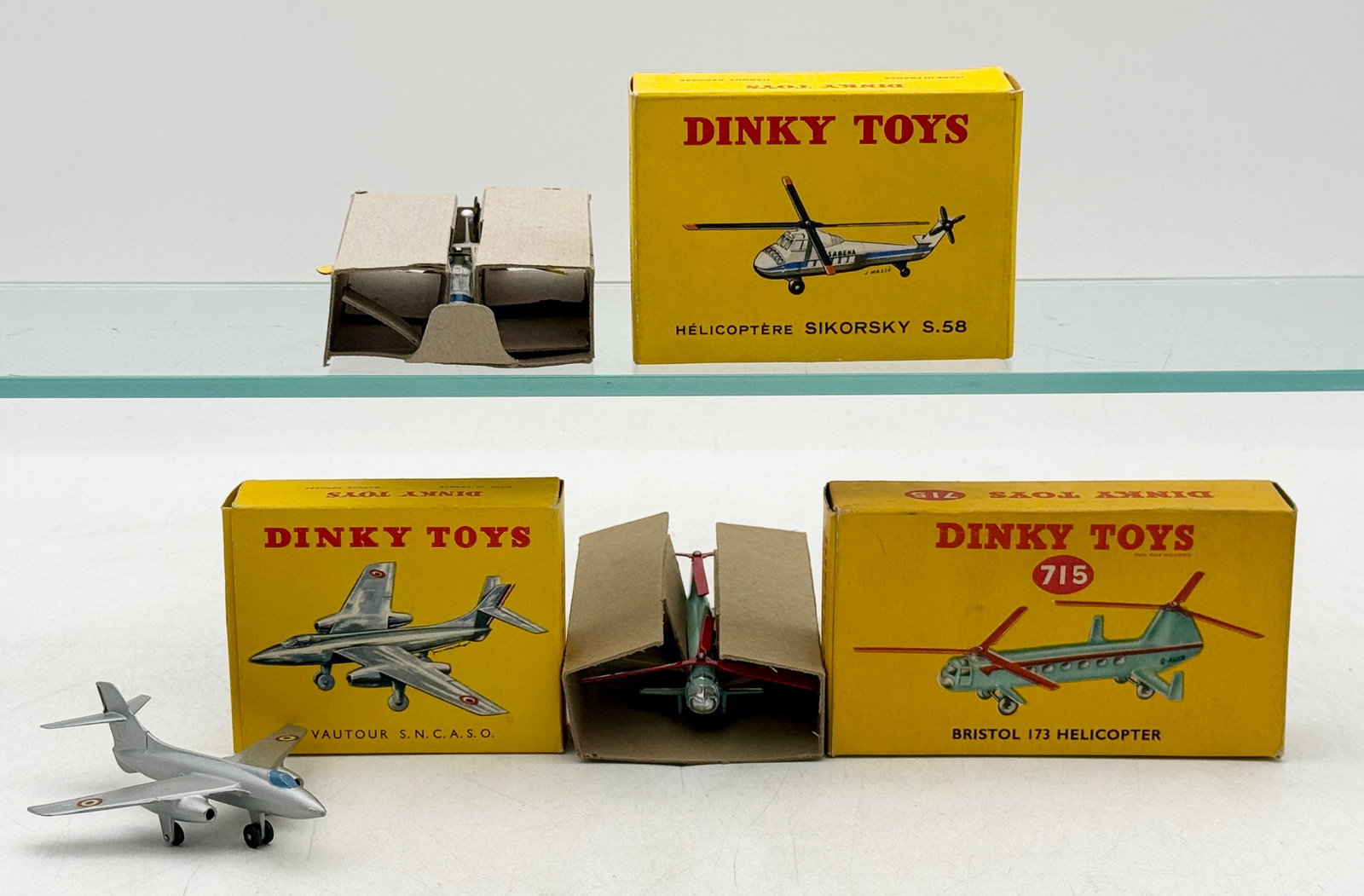 A Trio of Vintage Dinky Toys Die-Cast Model Aircraft: A trio of Dinky Toys die-cast metal aircraft comprising a Sikorsky S.58 helicopter, a Vautour S.N.C.A.S.O. jet, and a Bristol 173 helicopter. Each model retains its original paint finish and is accomp