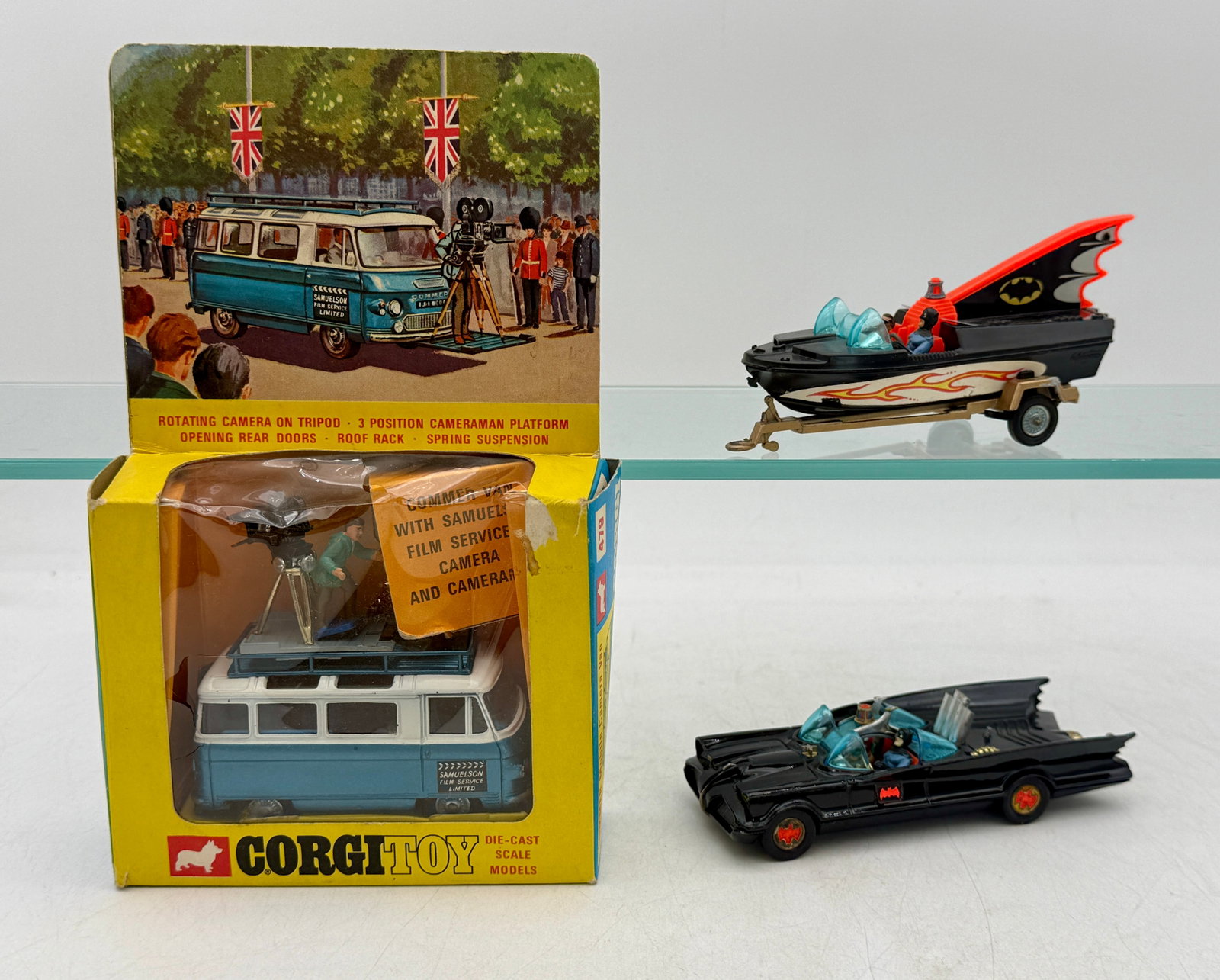 A Trio of Corgi Toys Die-Cast Batman and Service Vehicles: This collection includes a Corgi Toys No. 479 Commer Van in its original window box and loose Batmobile and Batboat models. The die-cast vehicles feature original paint finishes, including blue and wh