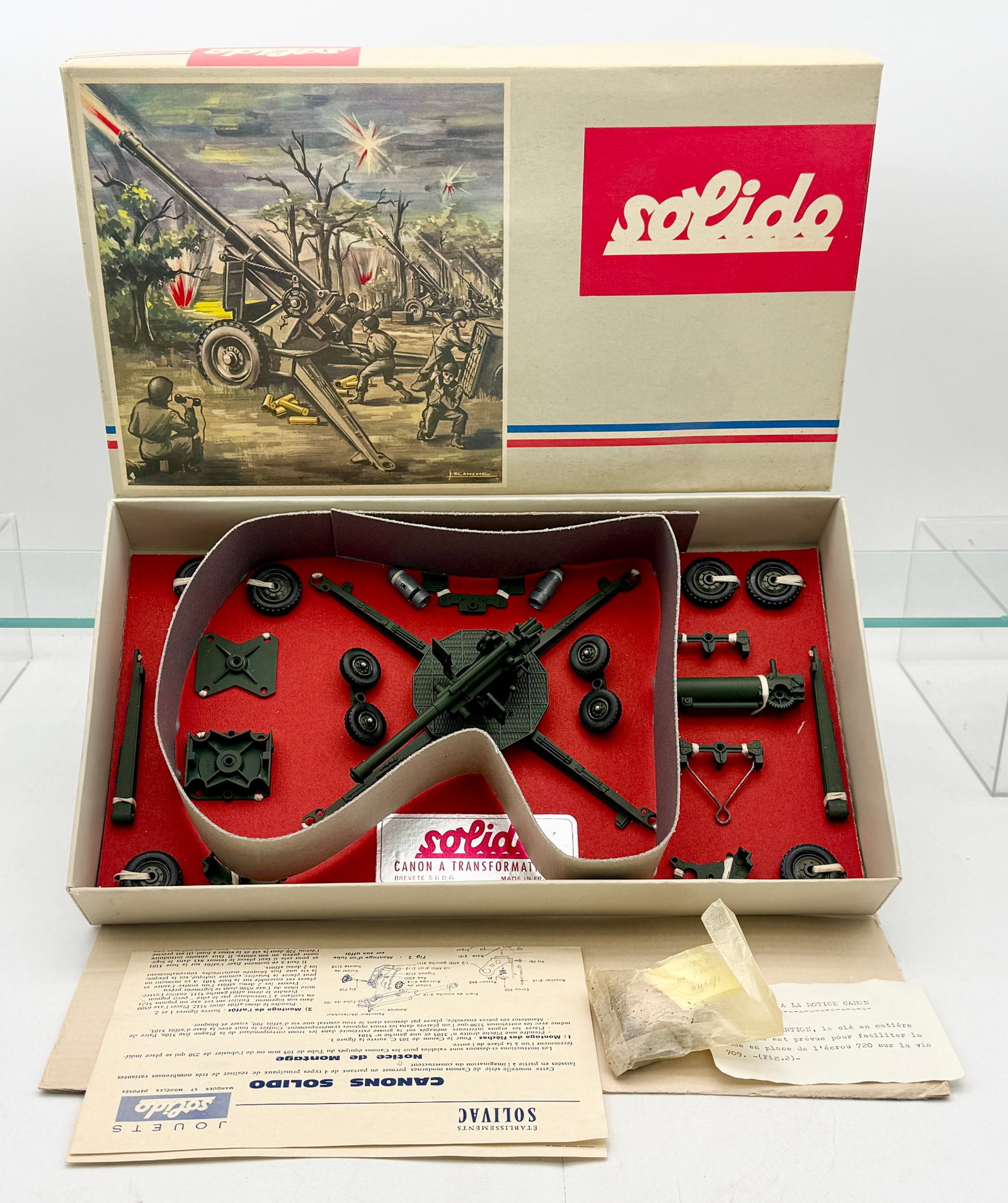 Solido Artillerie A Canons ? Construire Vintage Military Model Kit: A Solido Artillerie A military model kit featuring various olive drab plastic and diecast components for artillery assembly. The set is housed in its original lidded box with a color-illustrated scene