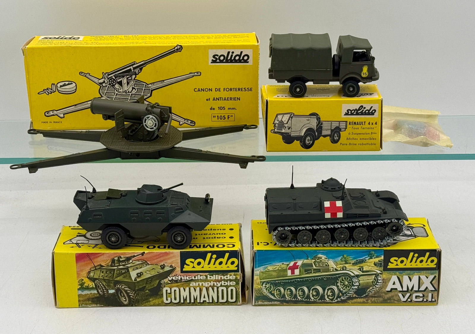 A Collection of Vintage Solido Die-Cast Military Vehicles: A collection of vintage Solido die-cast military vehicles and artillery pieces manufactured in France. The group includes a 105mm fortress gun, a Renault 4x4 truck, a Commando amphibious vehicle, and 
