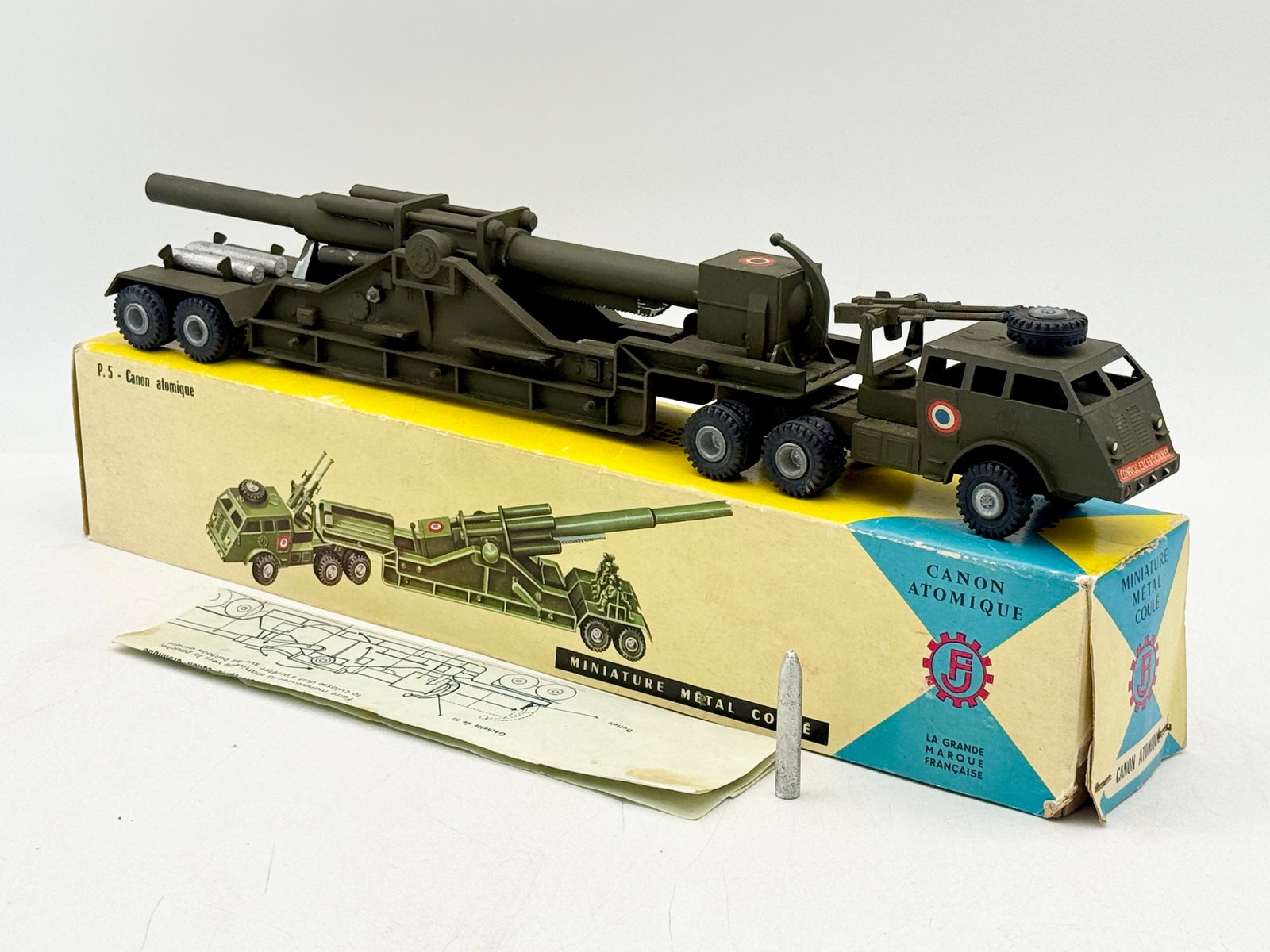 France Jouets P.5 Canon Atomique Set with Original Box: This France Jouets P.5 Canon Atomique set consists of a die-cast metal tractor and articulated trailer transporting a heavy artillery gun. The olive drab vehicle features tricolor decals and includes 