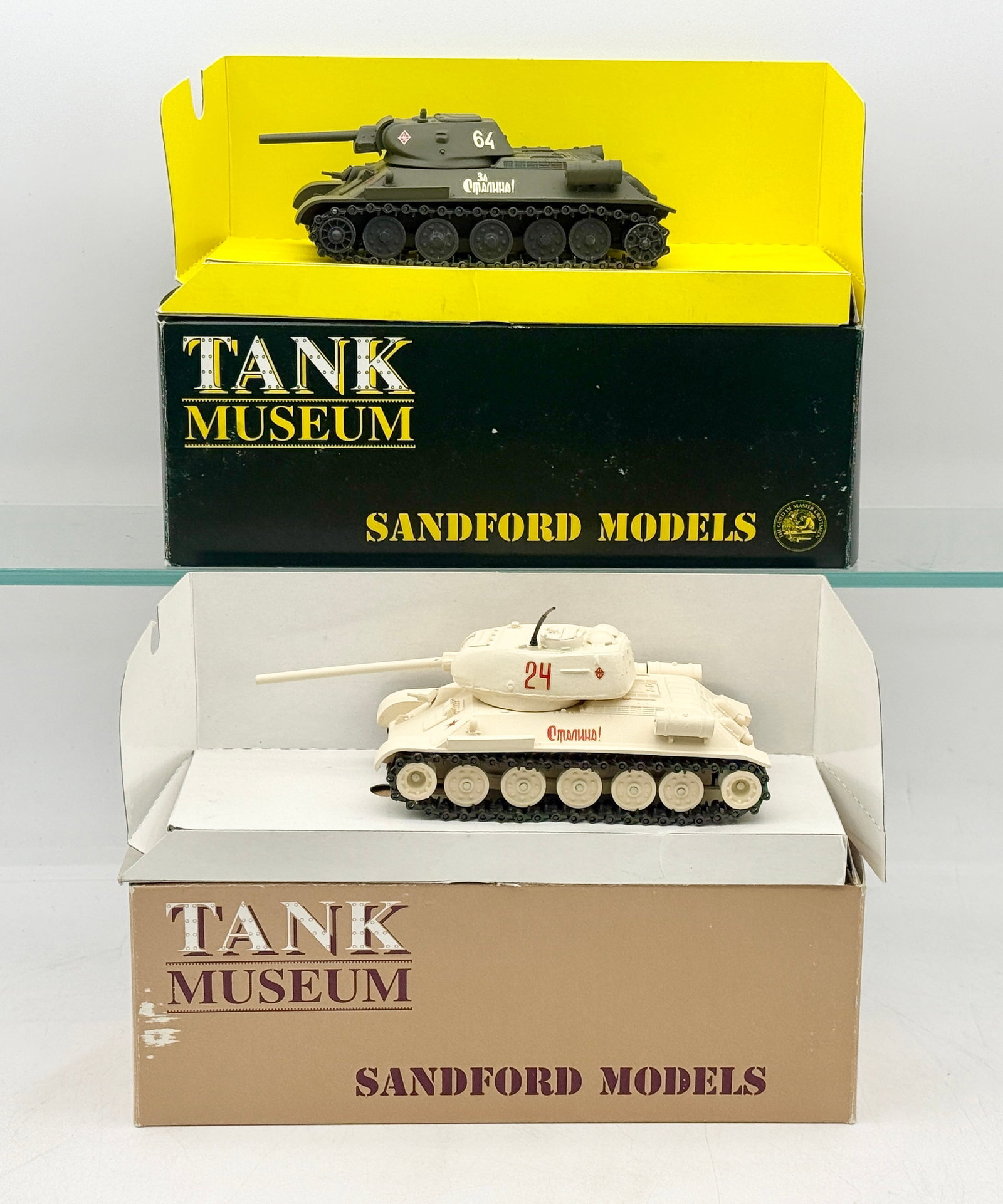A Pair of Sandford Models Soviet T-34/85 Tanks: A pair of Soviet T-34/85 scale model tanks produced by Sandford Models for the Tank Museum. The models are finished in olive green and winter camouflage schemes, featuring Cyrillic inscriptions, unit 