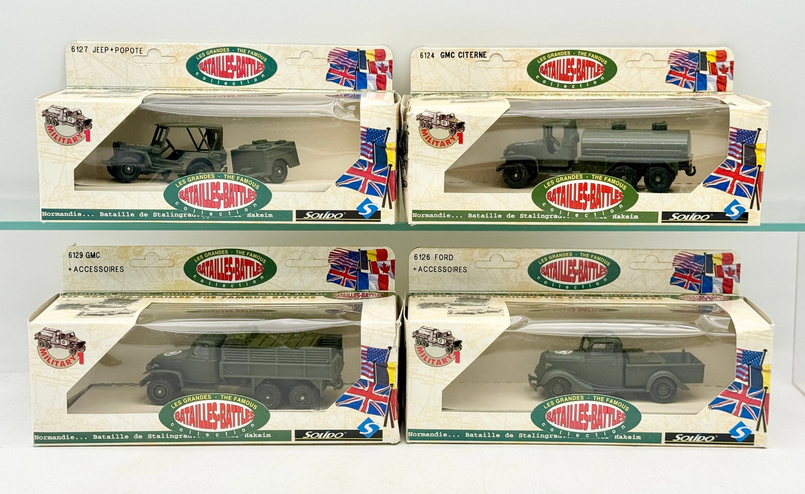 A Collection of Solido Military Die-Cast Vehicles in Original Boxes: A collection of Solido die-cast military vehicles from the Les Grandes Batailles-Battles series. Each olive drab model is housed in its original illustrated window box featuring historical battle loca