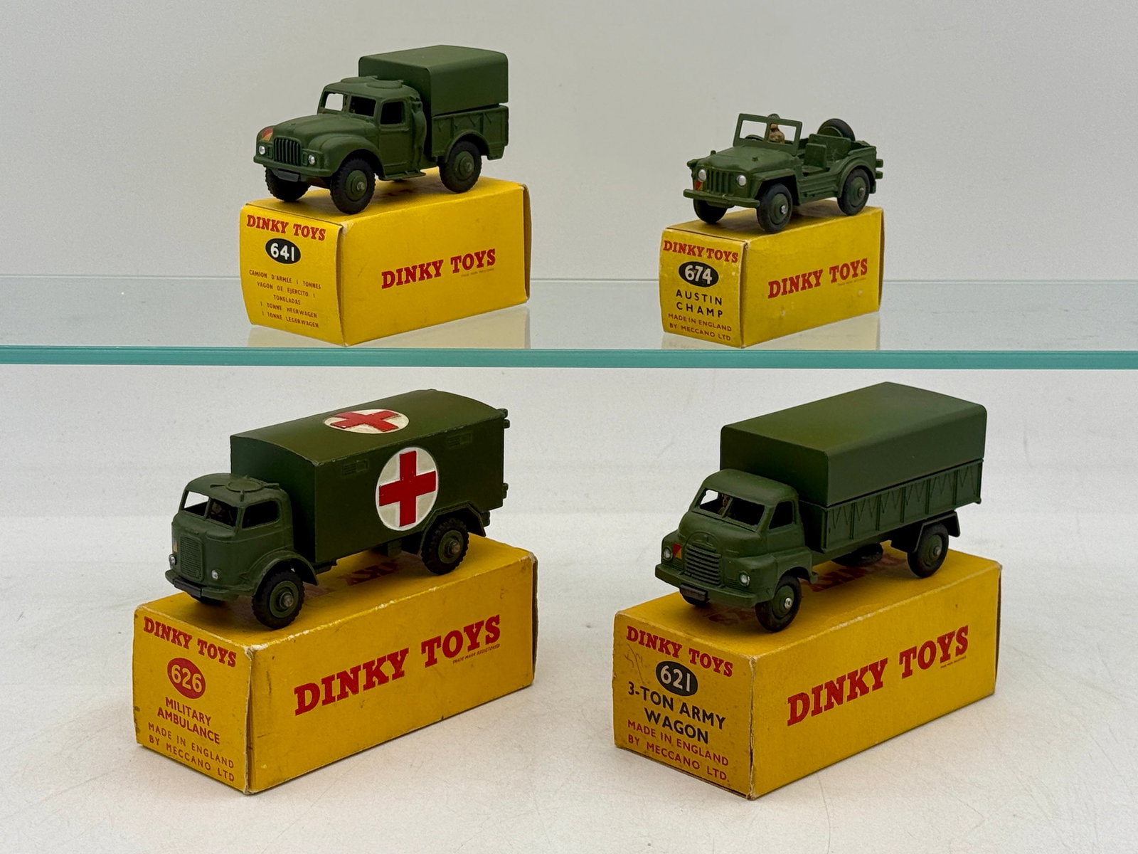 A Collection of Vintage Boxed Dinky Toys Military Vehicles: A collection of die-cast military vehicles by Dinky Toys, manufactured in England by Meccano Ltd. The olive drab assortment features a 3-ton army wagon, military ambulance, 1-ton cargo truck, and an A