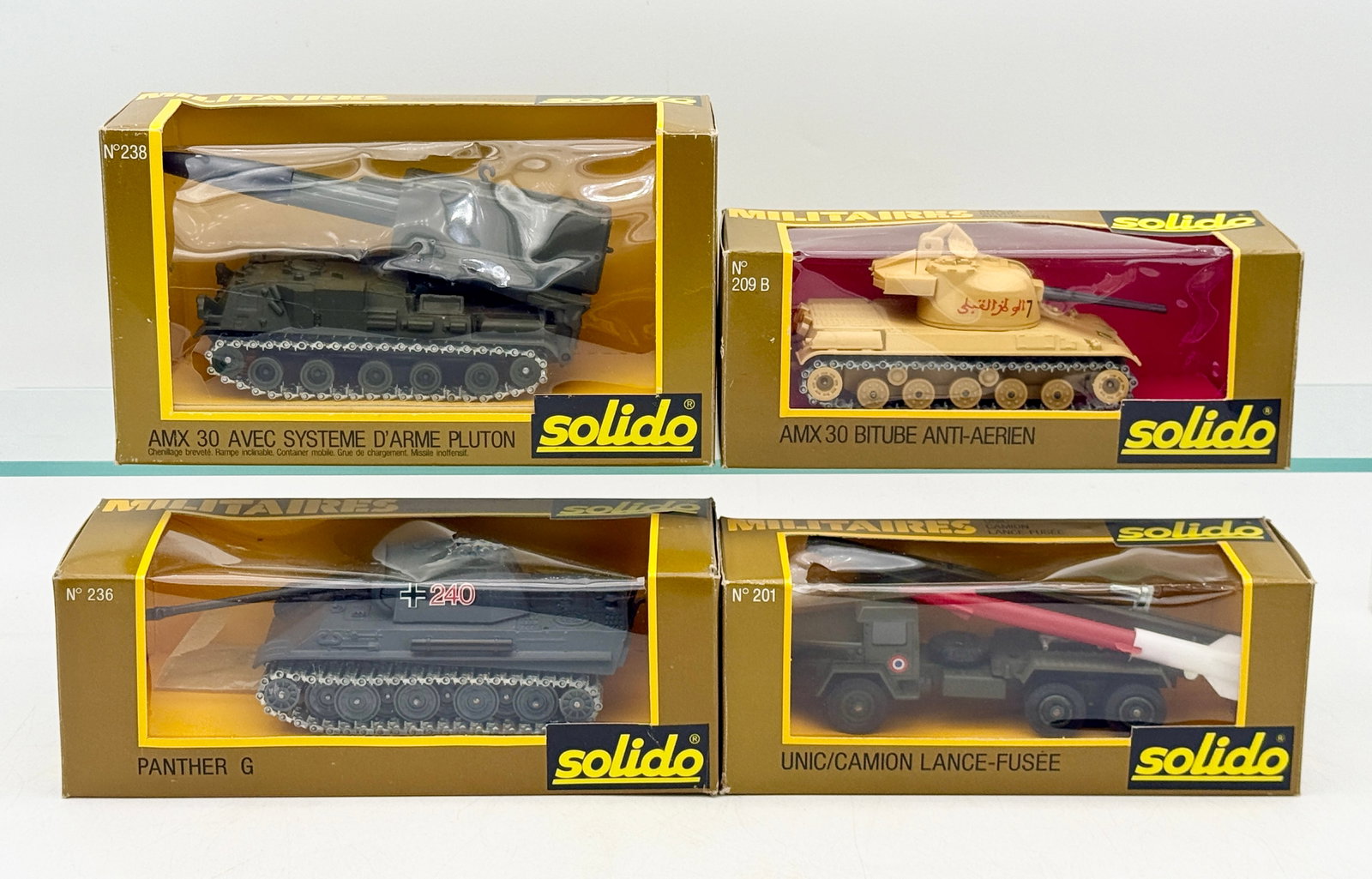 A Group of Vintage Boxed Solido Die-Cast Military Vehicles: This collection of Solido Militaires series vehicles includes an AMX 30 Pluton system, an anti-aircraft tank, a Panther G, and a missile launcher truck. Constructed from die-cast metal and plastic, ea