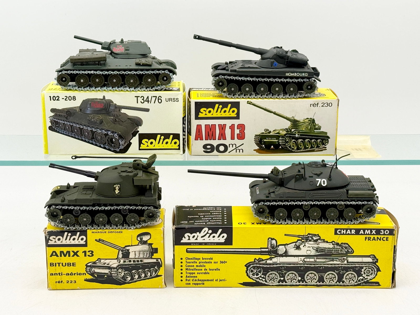 A Collection of Solido Military Tank Models in Boxes: A collection of French-made Solido die-cast metal military tanks, including a T34/76 URSS, AMX 13 90mm, AMX 13 Bitube, and a Char AMX 30. Each vehicle features articulated metal tracks and an olive dr