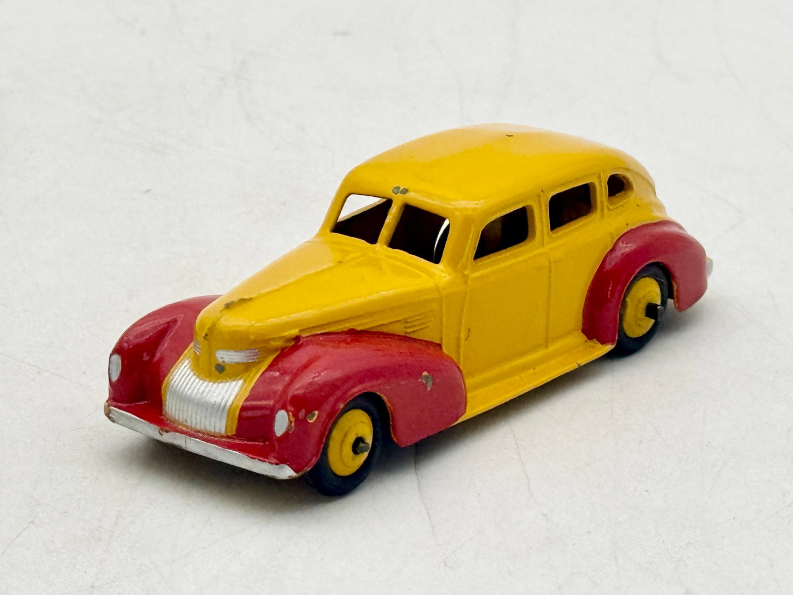 Attributed to Dinky Toys Chrysler Royal Sedan Die-Cast Model: Attributed to Dinky Toys, this model 39e Chrysler Royal sedan is constructed from die-cast metal with a yellow body and contrasting red fenders. The streamlined form includes a split windshield, silve