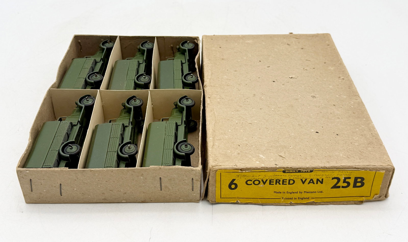 A Set of Dinky Toys 25B Covered Vans with Box: This set of Dinky Toys 25B Covered Vans features six die-cast vehicles finished in olive green paint. Each miniature truck is designed with a covered rear bed, integrated headlights, and black wheels 
