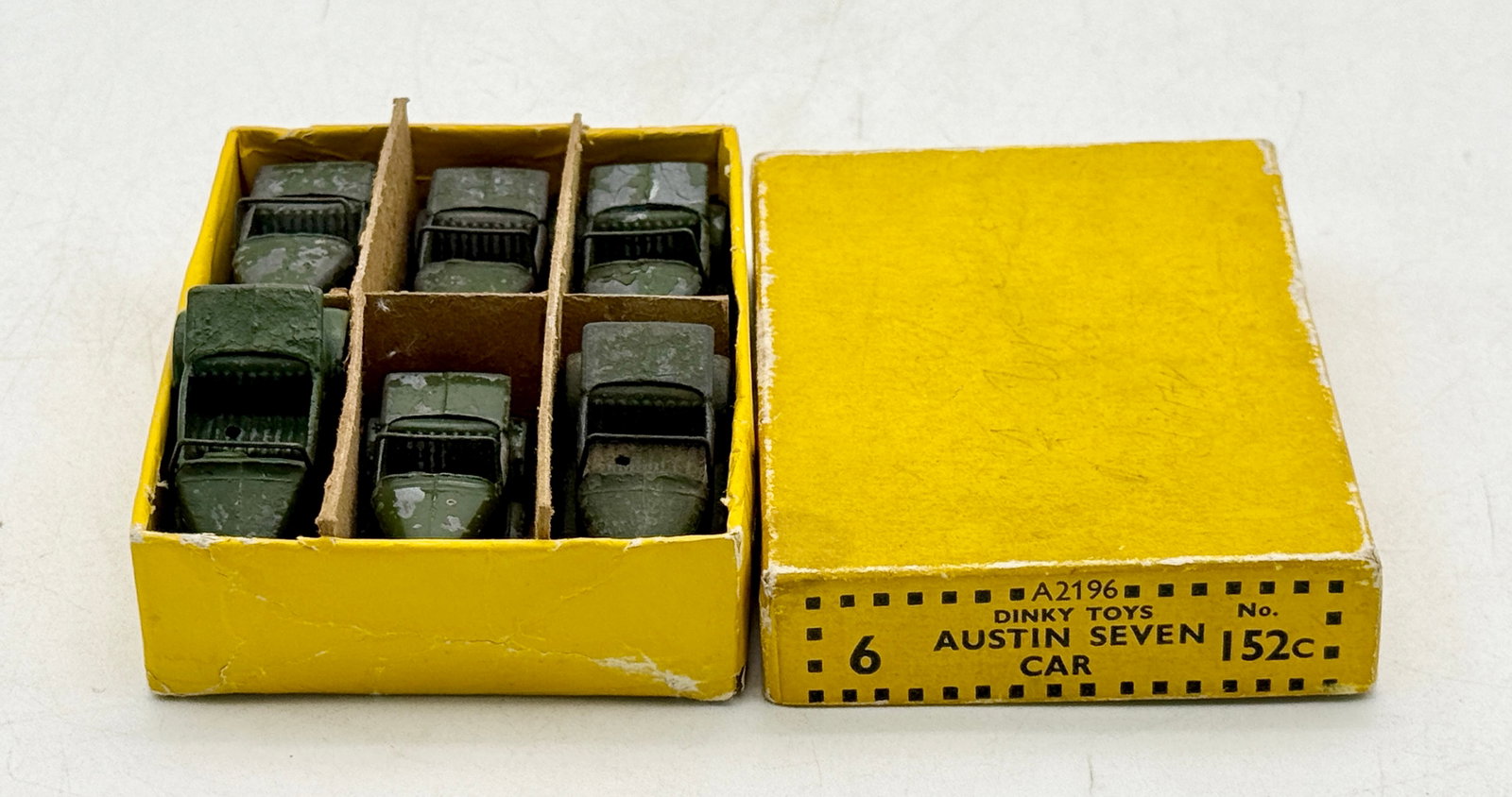 A Set of Dinky Toys Austin Seven Die-Cast Cars: A set of Dinky Toys Austin Seven open-top tourers manufactured by Meccano Ltd. in Liverpool. These die-cast metal vehicles are finished in olive drab green and housed in their original yellow trade bo