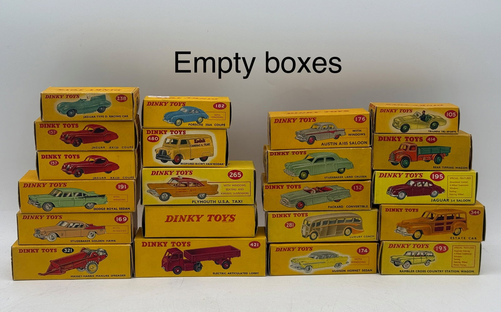A Collection of Vintage Meccano Dinky Toys Empty Boxes: This collection of original yellow cardboard boxes was manufactured in England by Meccano Ltd. for the Dinky Toys die-cast model series. The assortment features illustrated side panels with correspond