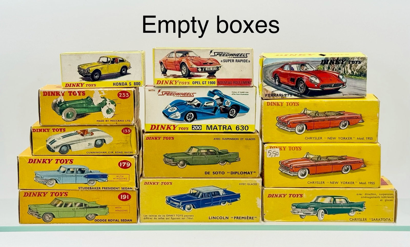 A Collection of Vintage Dinky Toys Empty Cardboard Boxes: A collection of vintage cardboard toy vehicle boxes manufactured by Dinky Toys and Meccano. Each item is constructed from printed yellow cardboard and features color graphic illustrations of various c