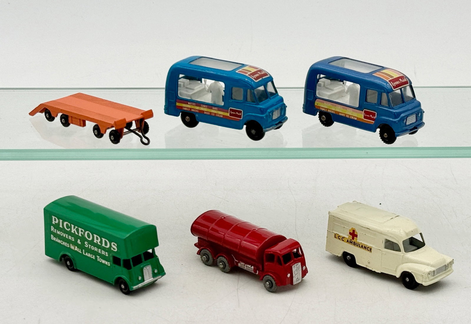 A Collection of Vintage Matchbox Lesney Die-Cast Commercial Vehicles: A collection of die-cast metal toy commercial vehicles attributed to Matchbox by Lesney. The assortment includes models with 47B2, 47B4 Lyons Maid, 46B7 Pickfords, and 11B2 Esso Road Tanker alongside 