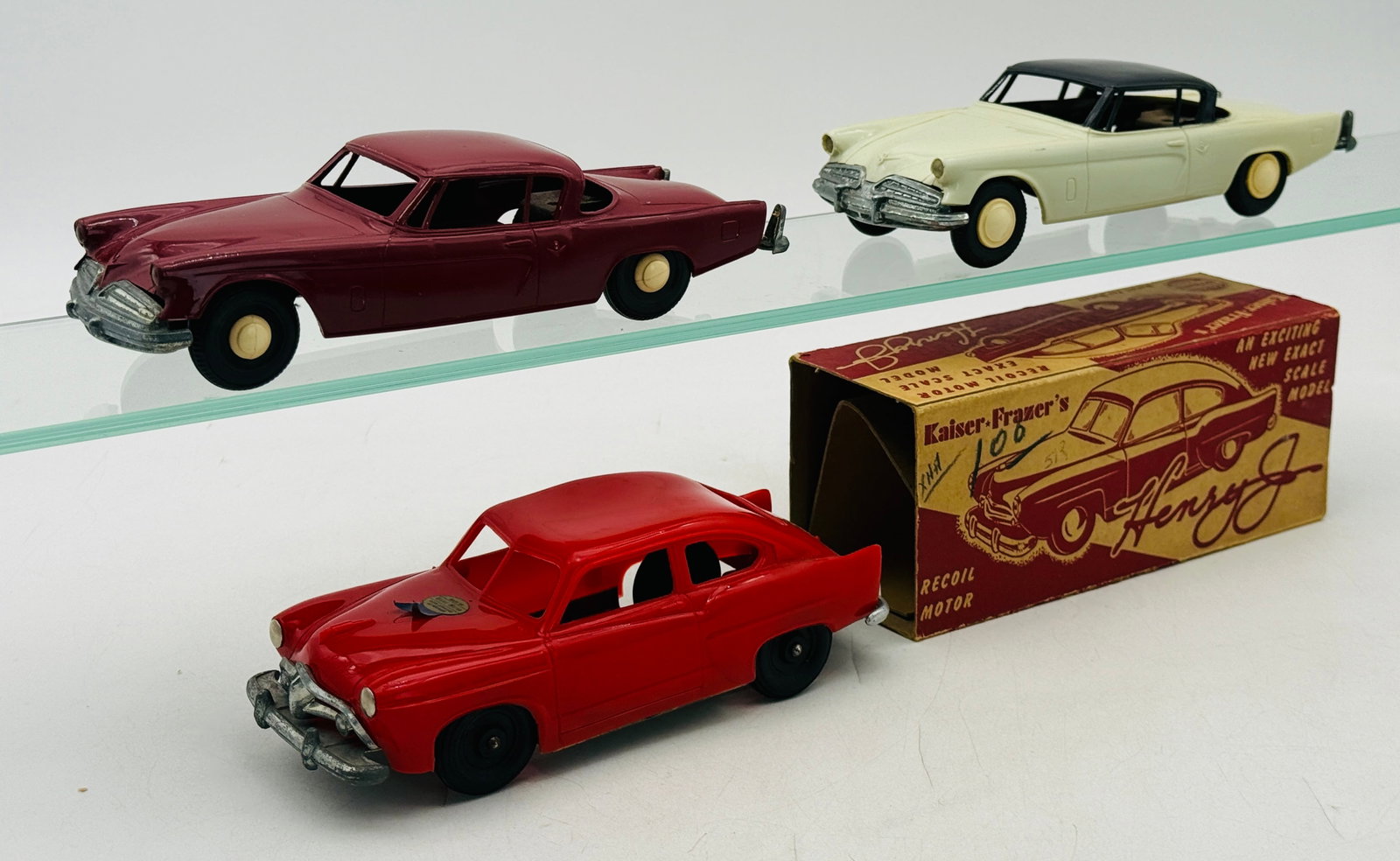 3 Vintage AMT and 'Henry J' Kaiser Plastic Promotional Model Cars: This collection includes a red Henry J Kaiser-Frazer Lincoln Line coaster and two AMT 1954 Studebaker Commander Starliners friction working. The Henry J is housed in its original illustrated recoil mo