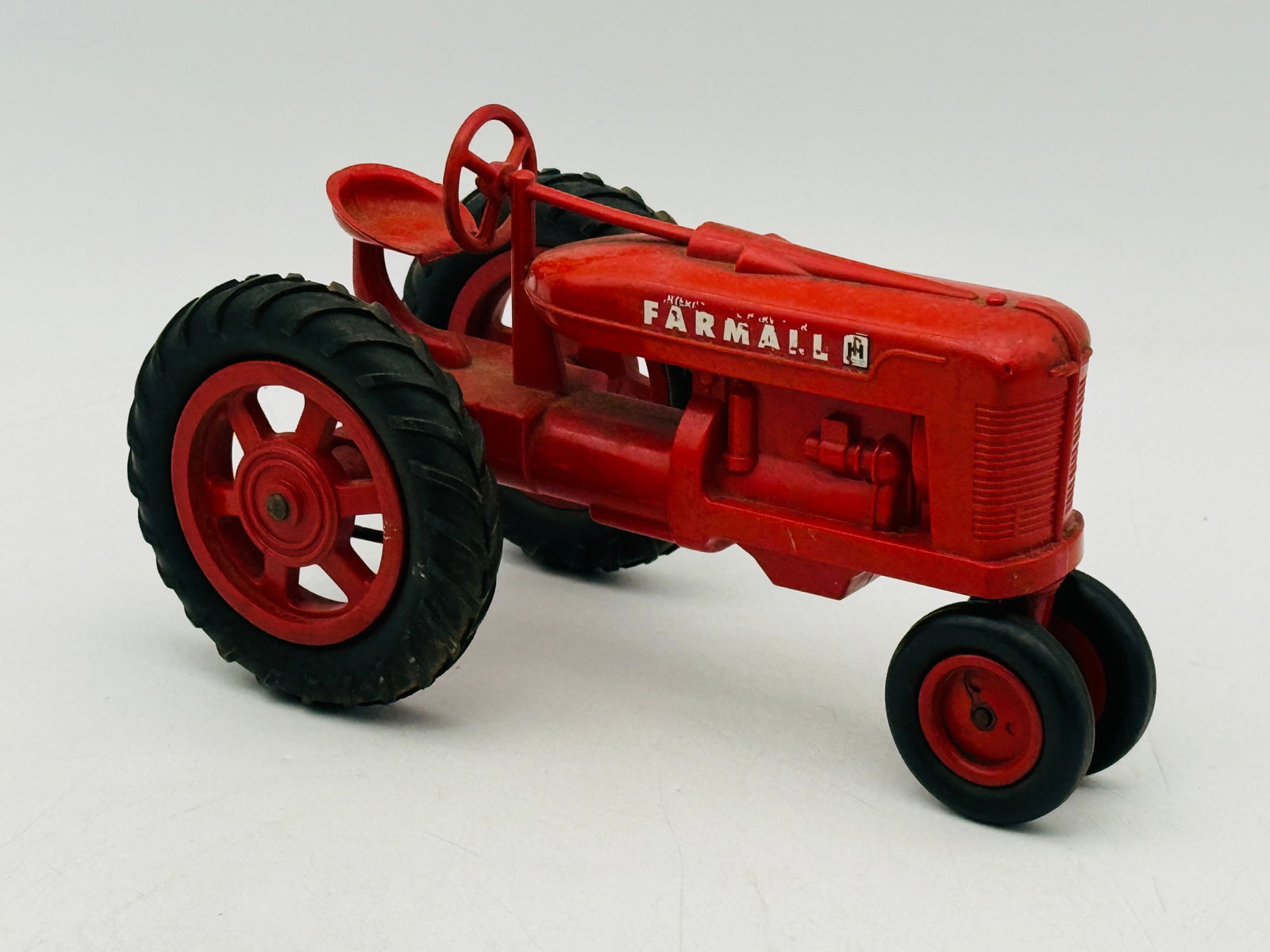 Product Miniature International Harvester McCormick Farmall Toy Tractor: Product Miniature Company International Harvester McCormick Farmall toy tractor constructed of die-cast metal. The model features a bright red finish with original decals on both sides of the hood and