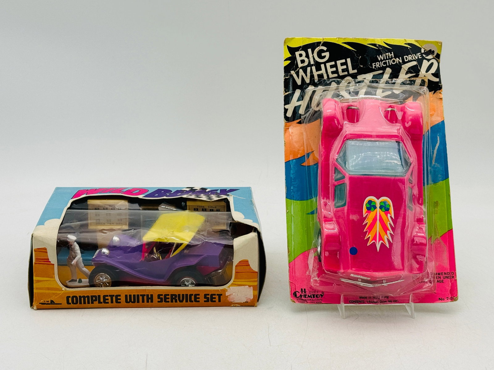 2 Vintage 1970s Chemtoy and Lucky Toy Vehicle Sets: Chemtoy Corporation and Lucky Toy plastic vehicle sets including a friction-powered racer and a dune buggy service set. The hot pink Big Wheel Hustler remains sealed on its 1973 blister card, while th