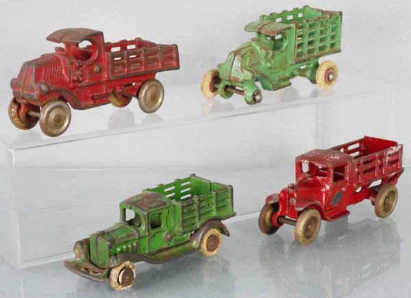 4 STAKE TRUCKS: painted cast iron, AC Williams, 4 3/4” long, Hubley, 4 1/2” long, missing 1 wheel, AC Williams, 4 1/2” long, rubber tires worn, Arcade, 4 3/4” long, C3-4.