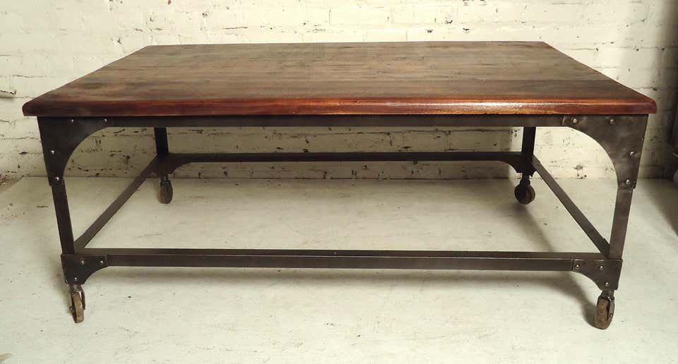 Industrial Wood Top Coffee Table: Metal frame base with a solid wood top given a rough rustic look. Exposed rivets and metal casters.---CONDITION DETAILSIndustrial Style - intentional industrial primitive look, weld marks, grind marks