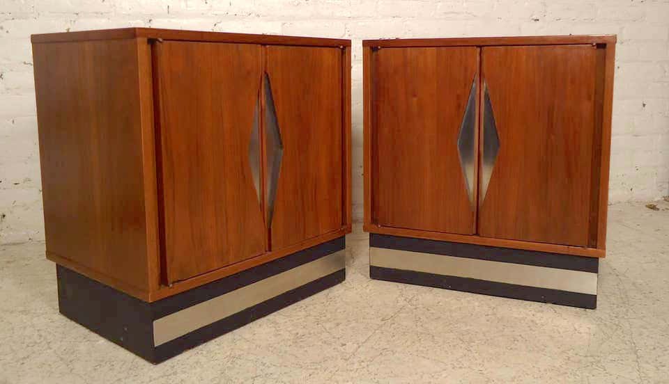 Pair of Mid-Century Modern Diamond Front Nightstands: This unique pair of vintage-modern nightstands features a chrome diamond front design sculpted in the center of two doors. Made of rich walnut grain and sits on a sturdy black base, each contains one