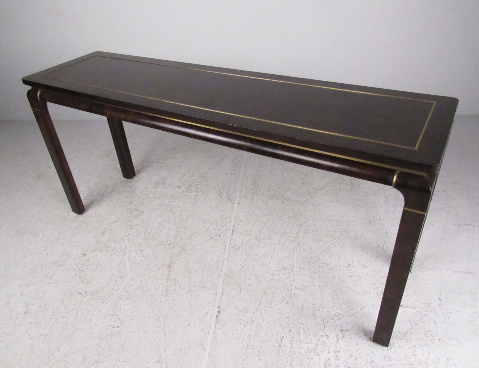 Mid-Century Console Table by John Stuart Inc: This vintage console table by John Stuart features a stylish Mid-Century design with dark burl lacquered finish and brass trim. Floating style tabletop accentuates the elegant appeal of this table, pe