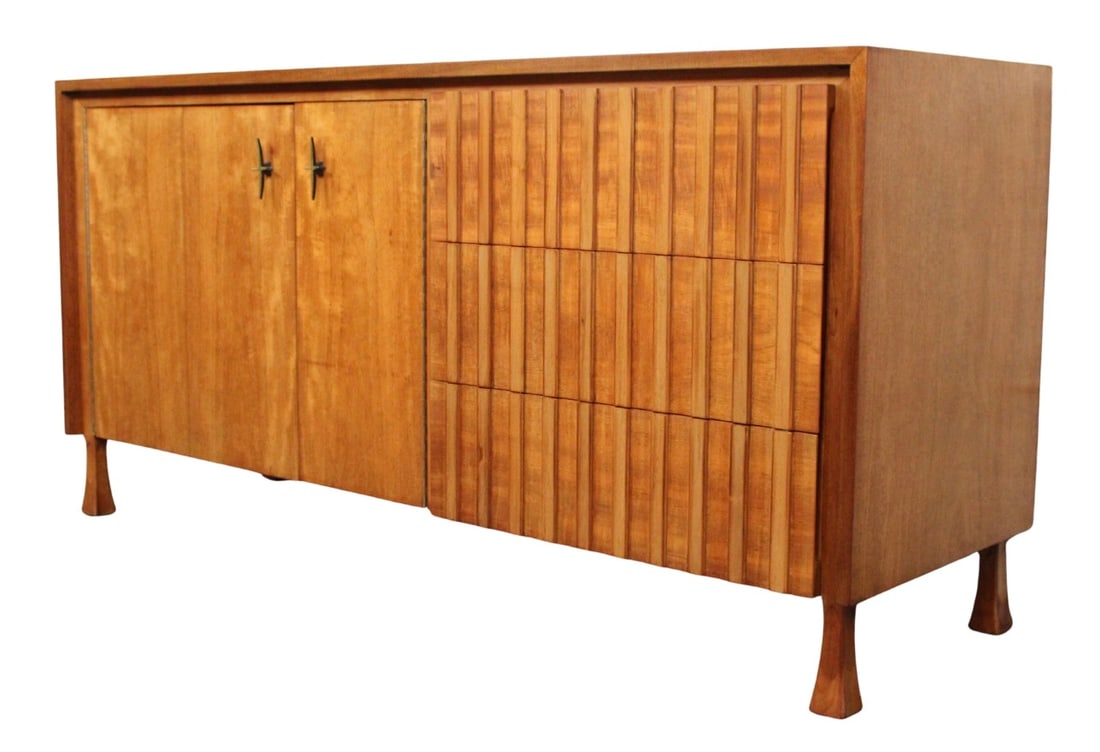 John Widdicomb Dresser: Mid-century modern walnut credenza by Widdicomb with six drawers. Three drawers are hidden behind bi-fold doors, and three are blended by a sculpted front design. Brass star handles, flared legs, brig