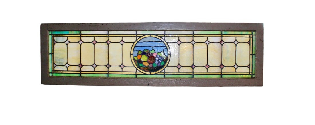 Long Stained Glass Transom: This window is over five feet wide, with a cornucopia centered. Wonderful coloring in each glass panel, and leaded designs throughout. Currently housed in a wooden frame - the overall dimensions are