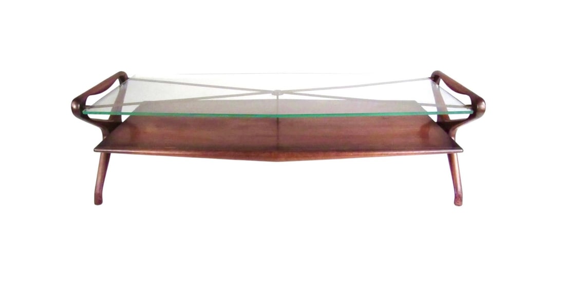 Italian Mid-Century Two-Tier Glass Coffee Table in the Style of Ico Parisi: This stunning vintage modern coffee table features unique sculpted wood frame, brass finish details, and thick glass top. Two-tier construction allows for added storage and display, while the Italian
