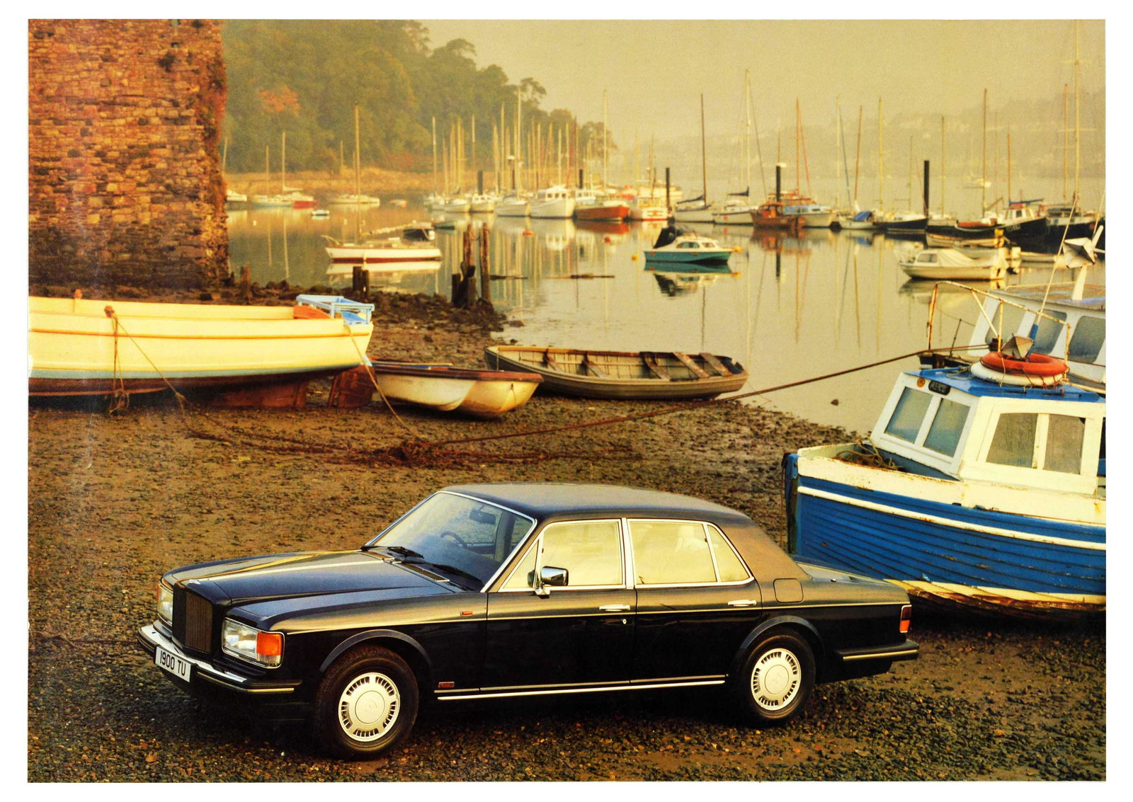 Advertising Poster Bentley Silver Spirit Docks Sailboat: Original vintage advertising poster for Bentley featuring a photograph of a Silver Spirit model car at the docks with oar boats and sailboats in the background. Bentley is a British manufacturer of lu