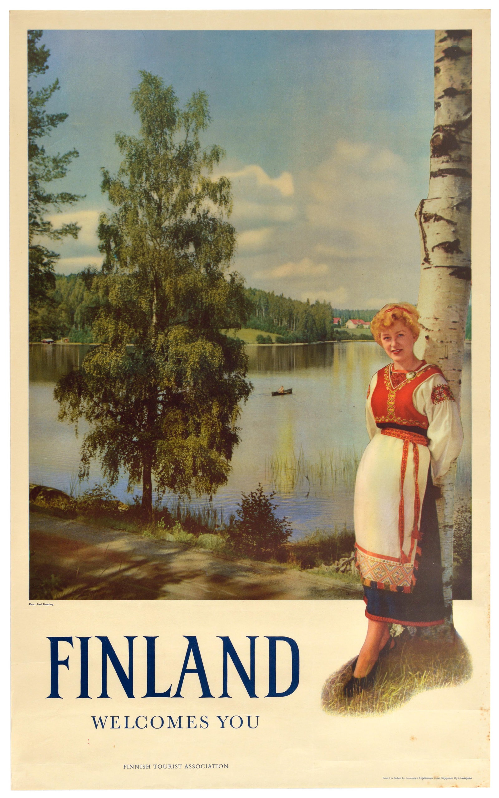Travel Poster Finland Welcomes You Lake Birch Traditional Costume: Original vintage Nordic travel advertising poster - Finland Welcomes You - featuring a young smiling lady dressed in a traditional folk costume, a red embroidered bodice, an apron, and a dark skirt, s