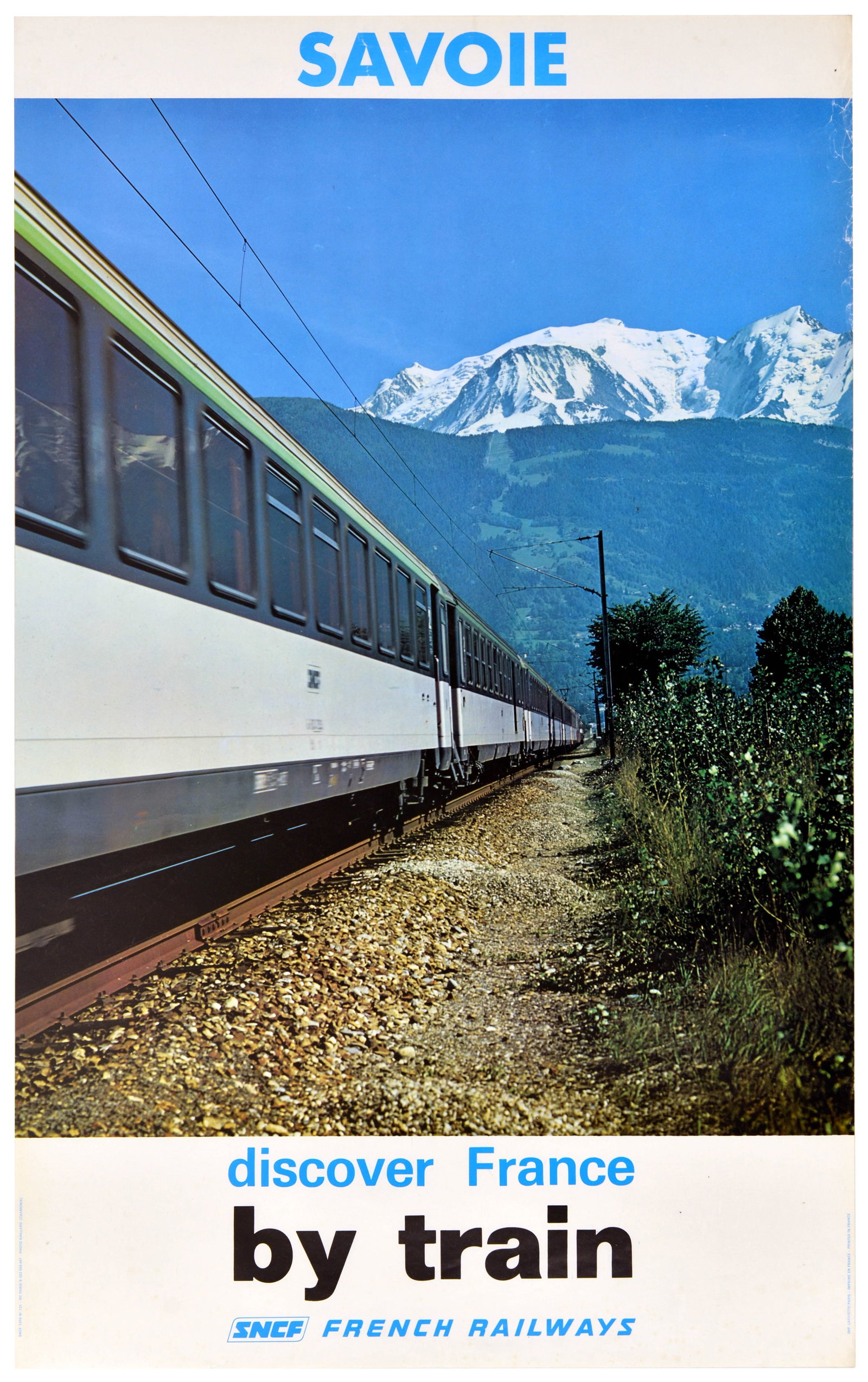 Travel Poster Savoie Ski France French Railways SNCF Train: Original vintage photographic travel poster for Savoie, issued by French Railways SNCF, featuring a dynamic, low-angle perspective of a long-distance SNCF train as it sweeps through the scenic French 
