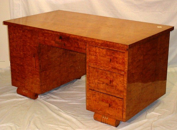 Art Deco burl walnut kneehole desk. The rectangula: Art Deco burl walnut kneehole desk. The rectangular top over a center frieze drawer flanked by three drawers and a cabinet door on rolled feet. H: 29 3/8" W: 55 1/2" D: 31 7/8" En suite to previous lo
