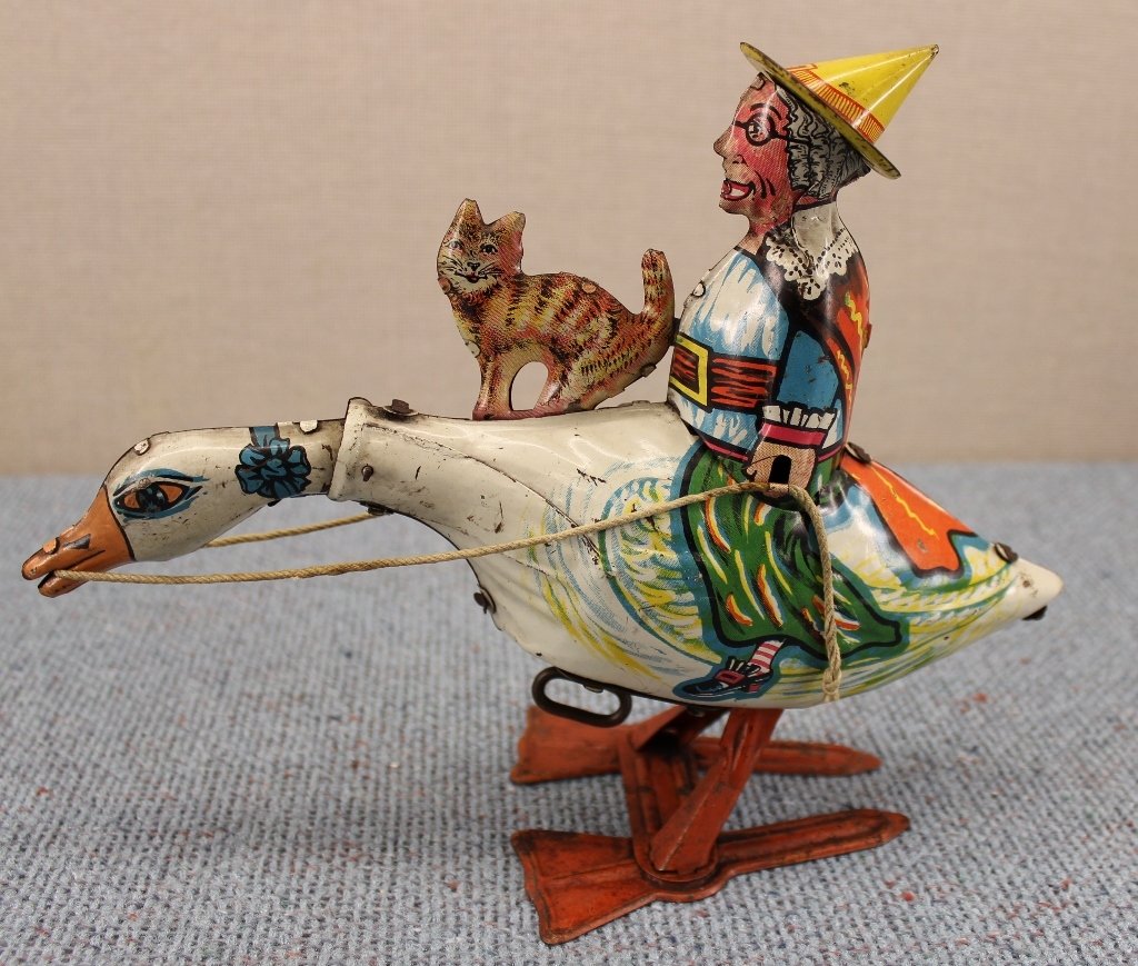 1920's Marx Old Mother Goose Tin Wind Up Toy: Goose bobs up and down and jumps around when wound. Toy shows Mother Goose and her orange tabby cat. Still in very good condition. 9 inches long, 7 inches tall.