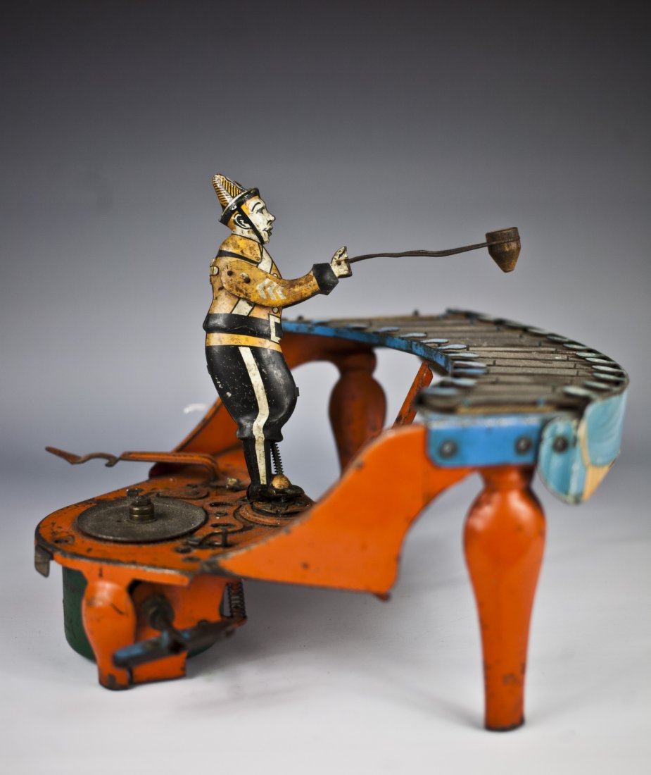Wolverine No. 48 Zilotone Toy: Wolverine Mfg., tin and pressed steel musical toy depicts figure at play on zilotone, colorful keyboard, orange instrument, clockwork mechanism activates spinning records and drumming motion by figure