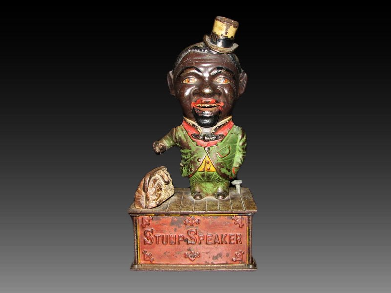 STUMP SPEAKER MECHANICAL BANK: BLACK AMERICANA BANK. 9 1/2" HIGH. POSSIBLE MINOR PAINT TOUCH UP. ORIGINAL COIN TRAP. EXCELLENT EXAMPLE. SEE PHOTOS FOR PAINT CONDITION.