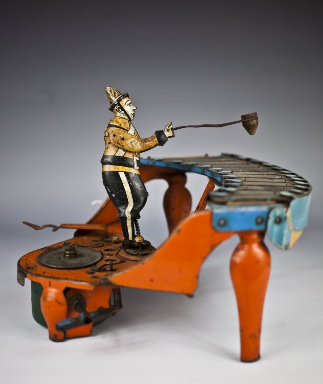 Wolverine No. 48 Zilotone Toy: Wolverine Mfg., tin and pressed steel musical toy depicts figure at play on zilotone, colorful keyboard, orange instrument, clockwork mechanism activates spinning records and drumming motion by figure