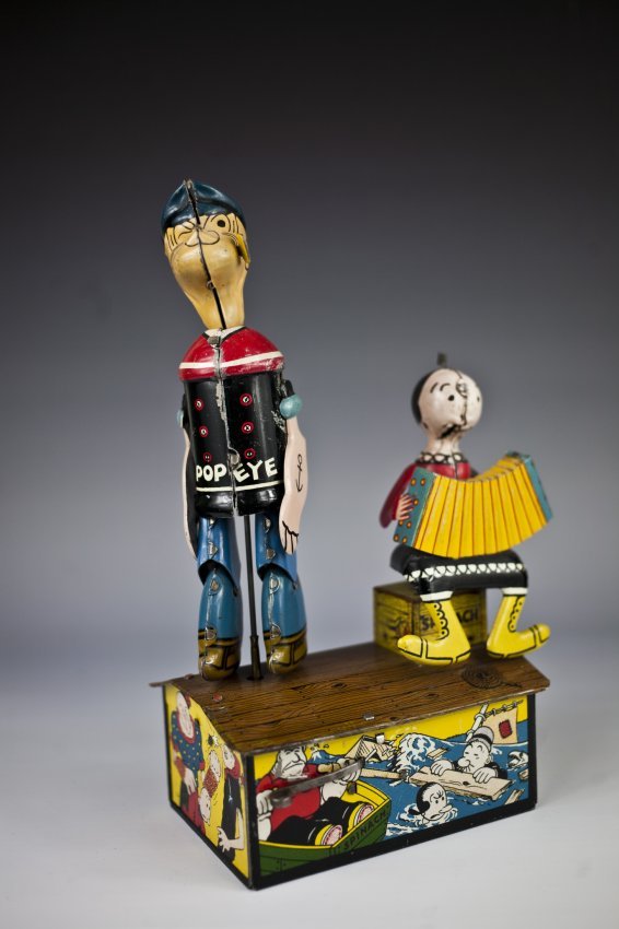 POPEYE & OLIVE OYL JIGGERS: Louis Marx, boxed example, lithographed tin, colorful graphics, classic toy depicts dancing Popeye figure and Olive Oyl playing accordion. 9 1/2" h.