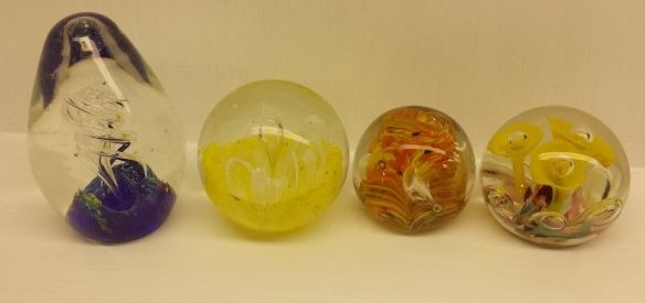 4 PAPERWEIGHTS: 3 round paperweights and 1 egg shaped paperweight. 1: Yellow flowers with pink, white, red, and blue bottom.2: orange , yellow, white and black swirl design.3: White flower inside a yellow design4: Eg