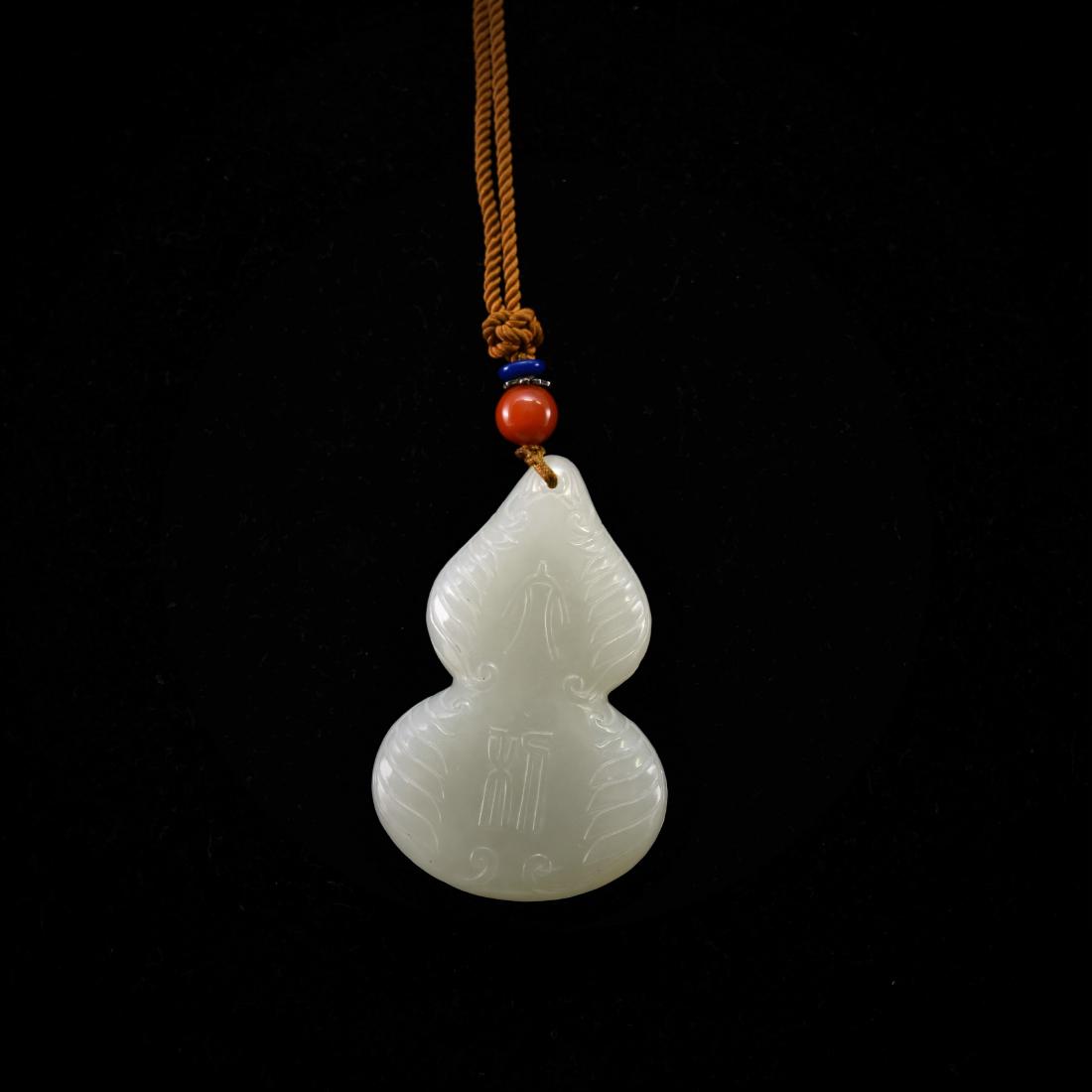 CARVED WHITE JADE OF DOUBLE GOURD PENDANT: Carved nephrite jade, of double gourd shaped, the main body carved in relief with DaJi characters, surrounded with flames motif to the edges. The jade shows clean white tone, with moist milky appearan