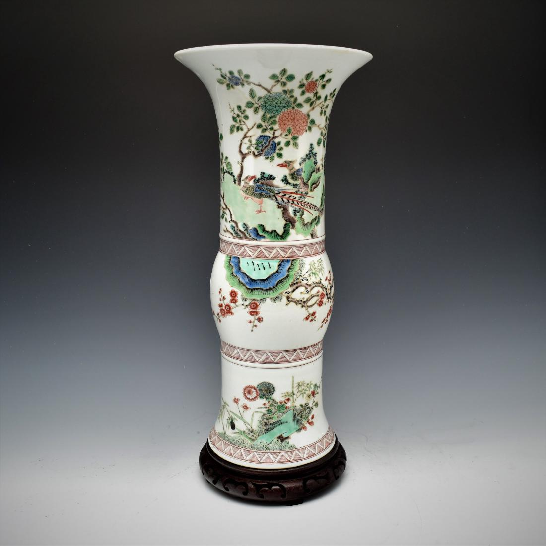 QING CHINESE FAMILLE ROSE GU VASE ON STAND: The Chinese beaker vase potted in shape of a traditional Gu form. The beaker having baluster shaped body, with bulging belly, trumpet-shaped neck are painted in vivid famille rose of pheasant within c