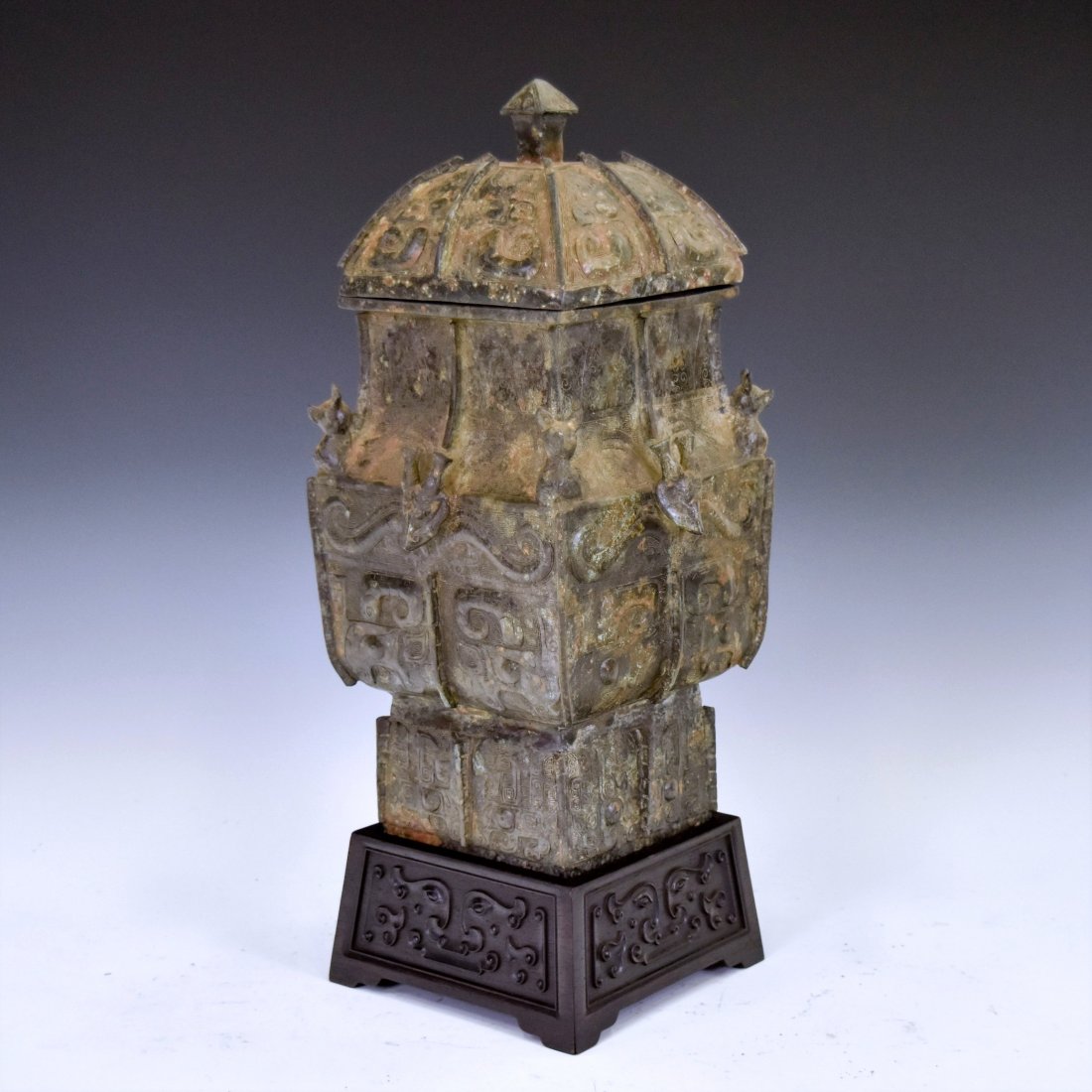 ANTIQUE CHINESE LIDDED SQUARE BRONZE CENSER ON STAND: Chinese bronze cast unto a square baluster shape form, wide and angled shoulder tapered toward prominent neck leading to a banded rim, raised upon a splayed foot base. The vase characterized with four