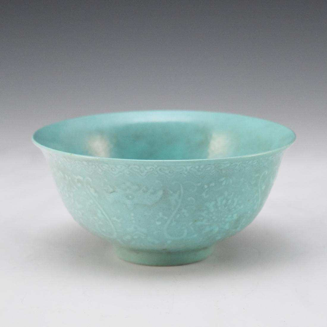 CARVED TURQUOISE MONOCHROME PORCELAIN BOWL: Finely potted Chinese porcelain in a deep vessel, with rounded cavetto rising a steep sides toward slightly flared rim, upon a ring footed base. The exterior decorated in shallow relief of stylized fl