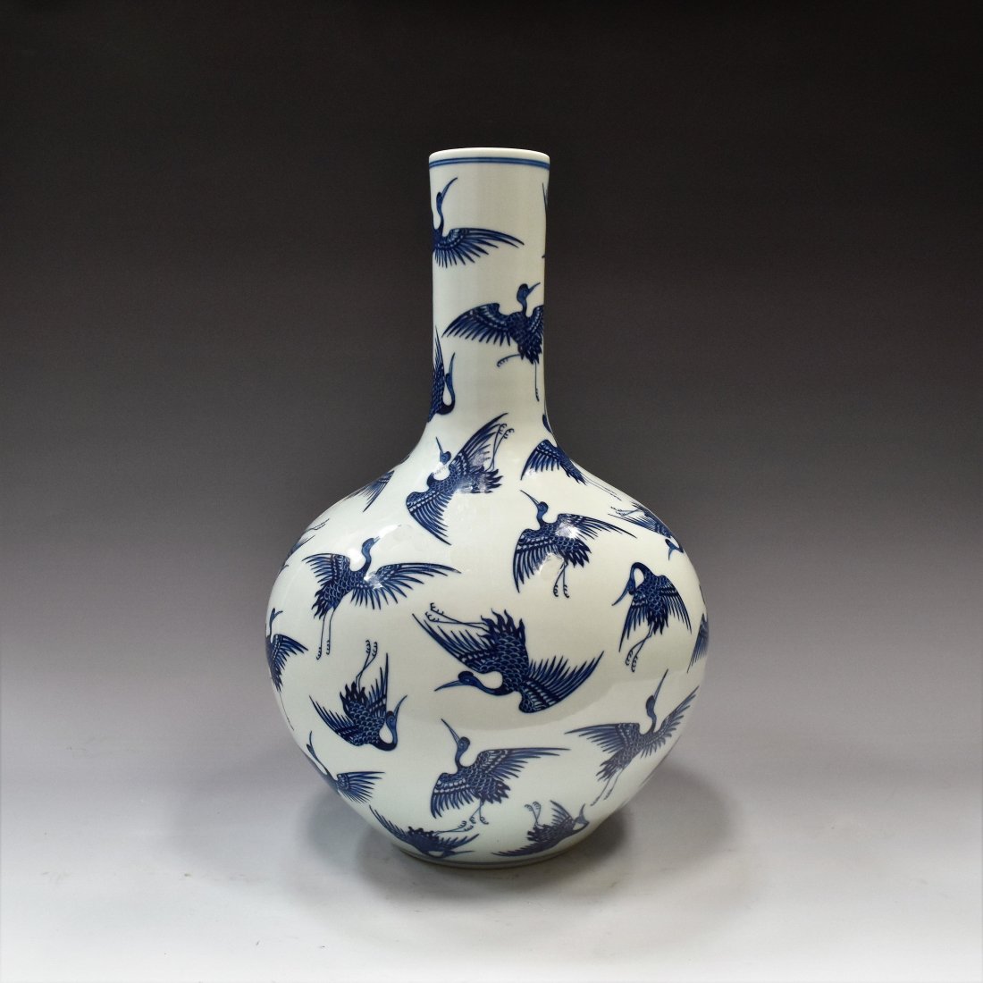 BLUE & WHITE HUNDREDS CRANES CELESTIAL VASE: Chinese porcelain potted in a celestial form, bulbous body with round shoulder gently tapered toward tall cylindrical neck, leading to slightly wider rim; raised upon a flat concaved base. The exterio