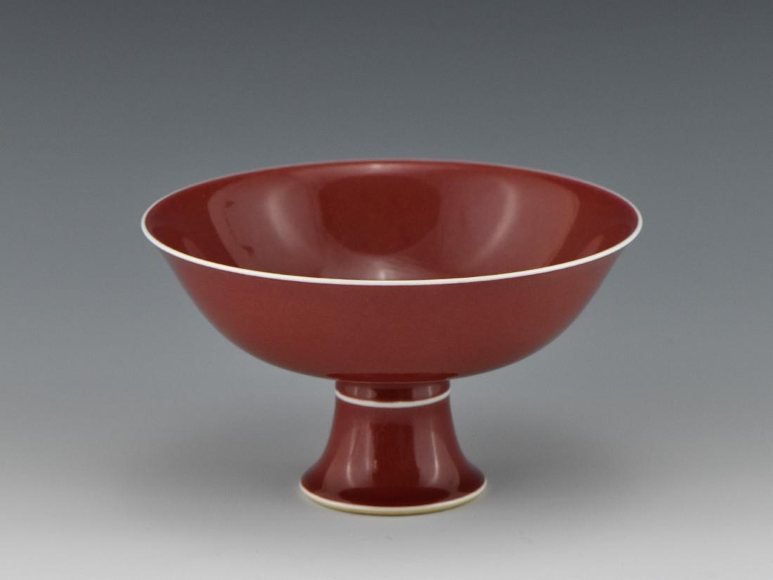 A QING COPPER-RED GLAZED PORCELAIN CENTERPIECE: A fine Qing ox blood porcelain center piece, the round cavetto everted slightly curved sides, raised on tall splayed footed base. The exterior covered evenly in monochrome copper-red underglaze, with 